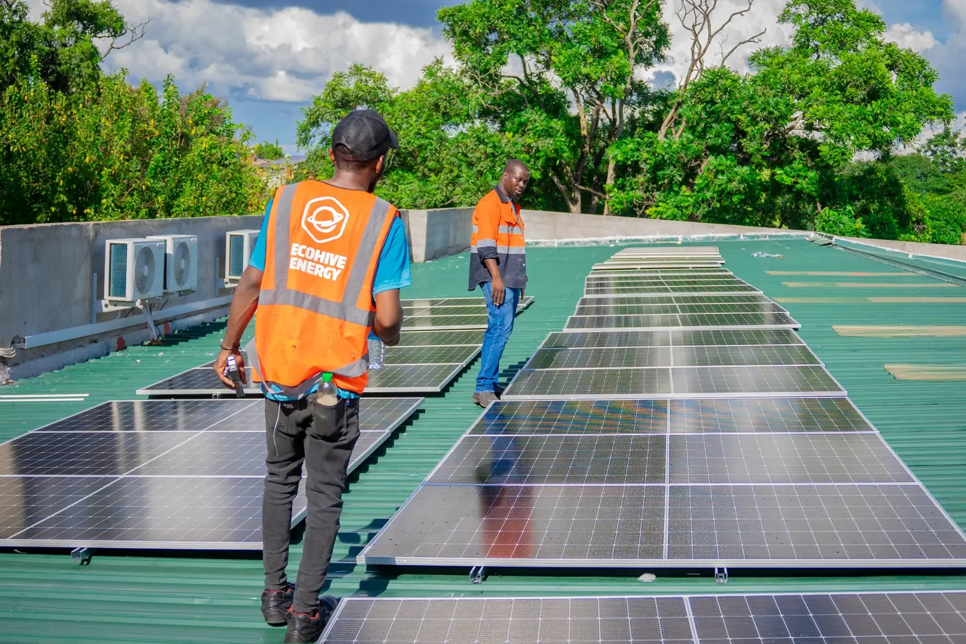 An EcoHive installer walking between long rows of newly mounted solar panels