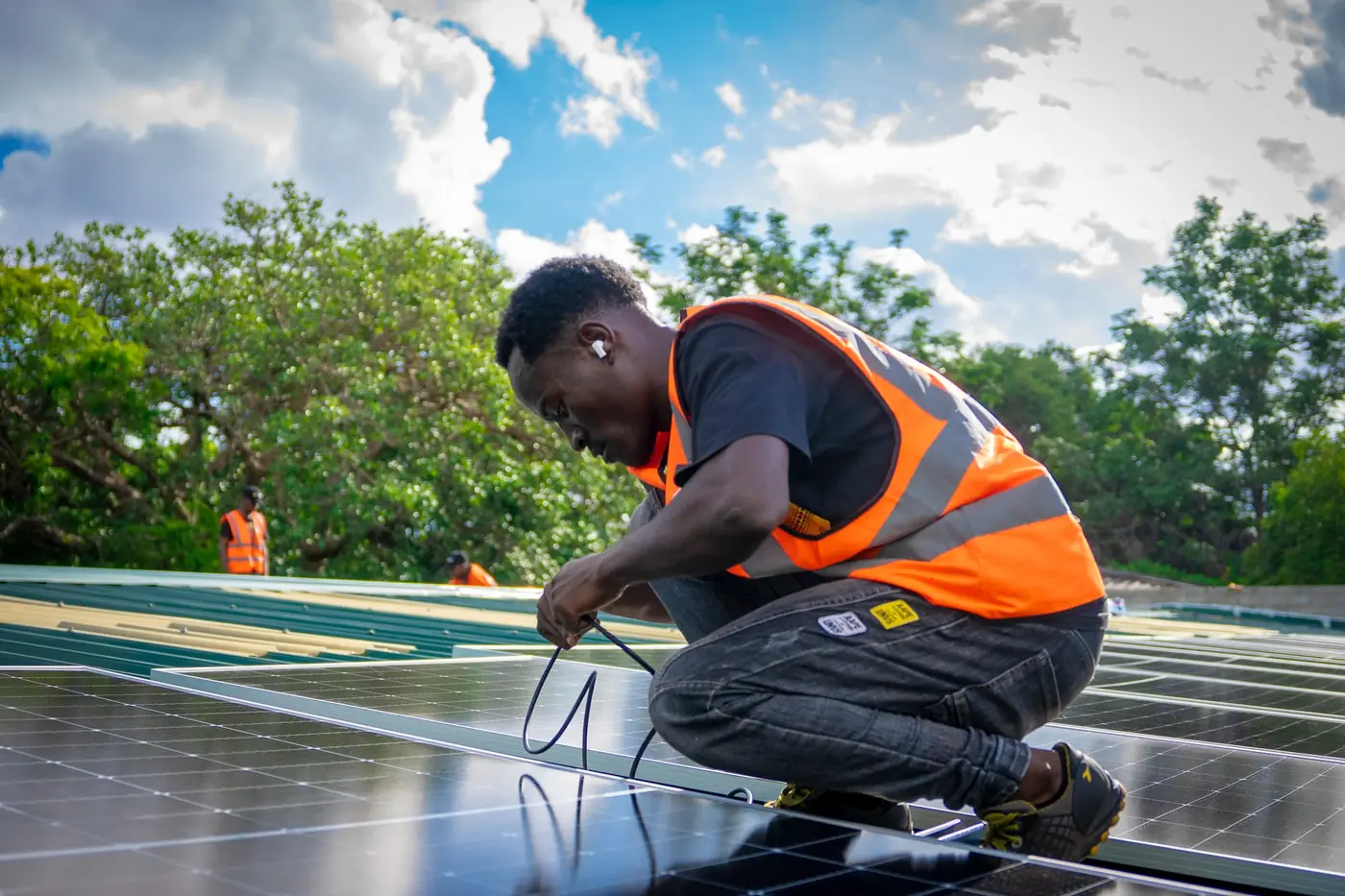 An EcoHive installer connecting solar panel cables on a rooftop array