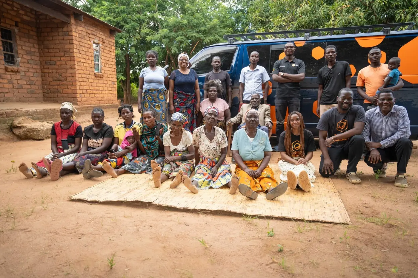 Lazaro Village residents seated on a mat with the EcoHive team standing behind them