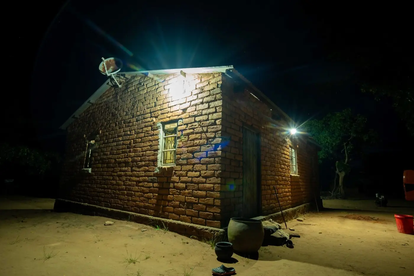 A brick house in Lazaro Village lit by its solar-powered light against the night sky